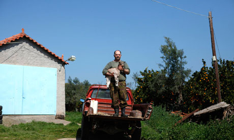 George Andrianakis, 56,poses with a goat in the yard of his farm in the village of Stafania, Greece.
