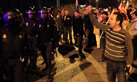 Union picketers shout slogans to riot police officers at the start of a general strike in Malaga