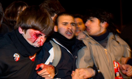 A man is seen bleeding after being struck by police during a national strike in Madrid.