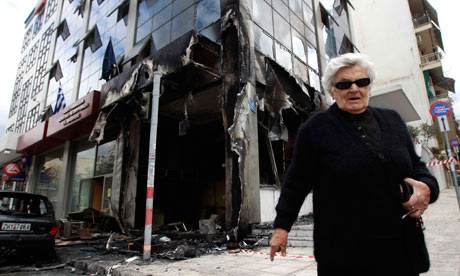 A woman walks in front of a damaged ministry building in Athens