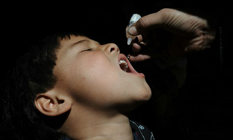 Afghan health worker administers polio vaccine to a child on the first day of a vaccination campaign