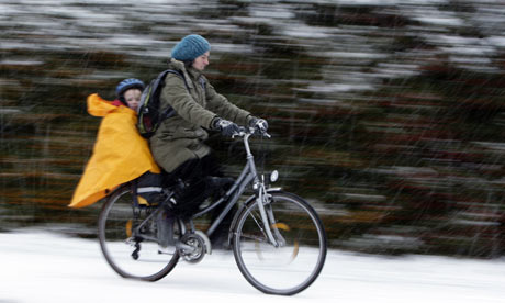A woman and child cycle through snow