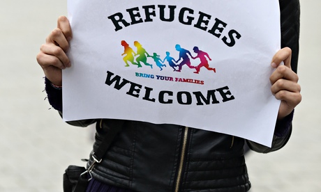 A woman in German holds up a 'refugees welcome' sign