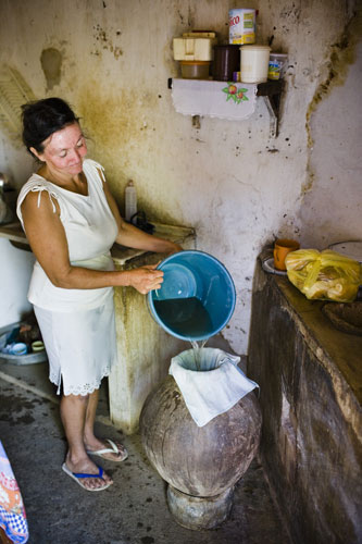 Gallery Brazil: Maria Aparecida Mendes da Silva uses an old cloth to filter the dirty water
