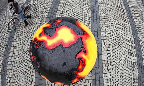 Copenhagen Diary : A woman with a bicycle walks next to a globe part of an installation COP15