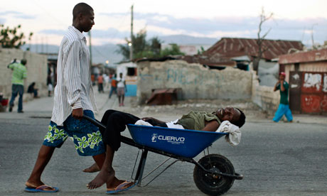A Haitian with symptoms of cholera is transported in a wheelbarrow in Port-au-Prince, Haiti