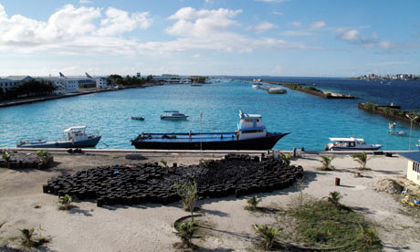 A small ship off-loads oil drums on the airport island of Hulhule in the Maldives