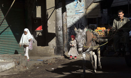 MDG : Egypt : Muslim girls walk past a donkey-pulled cart in the village of Sol, province of Helwan