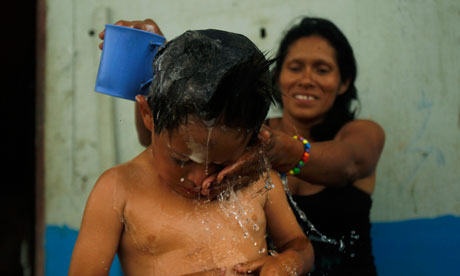 MDG : A woman bathes her son at the Cerro Candela shantytown in Lima , Peru