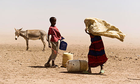 Two people and a donkey stand near water containers in Somalia