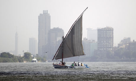 A man with his family travel on a home boat near garbage plants in the Egyptian Nile River in Cairo