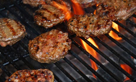 Hamburgers cooking on barbeque grill with flames