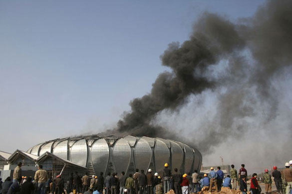 Gallery Week in sport: Workers watch smoke billow from an indoor stadium in Jinan
