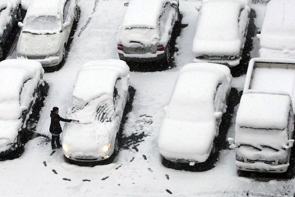 Gallery November 19 2008: Jeongeup, South Korea: A woman sweeps snow off her car