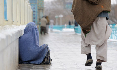 An Afghan woman sits on the ground as she begs next to Hazrat-e Ali shrine in Mazar-i Sharif on 