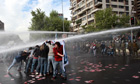 Demonstrators are hit by a jet of water during a rally in Santiago, Chile