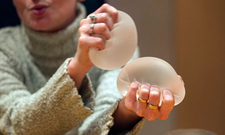 Alexandra Blachere displays silicone gel breast implants during an interview in Paris