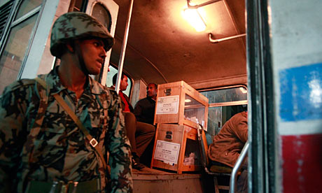 A soldier stands guard as election officials load ballot boxes after the polls closed, in Cairo.