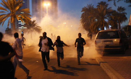 Protesters run from a cloud of teargas during a clash with Bahraini security forces