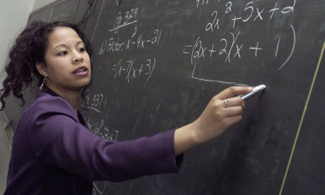 A teacher writes equations on blackboard 