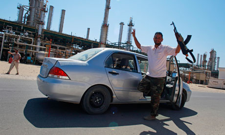 A rebel fighter gestures after rebels seized full control of the Zawiyah oil refinery.