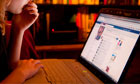Teini-ikäinen tyttö lukee hänen Facebook-sivu on kannettava tietokone kotona, UK
