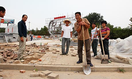 Migrant workers spray paint on a steel map monument in Daxing, southern Beijing