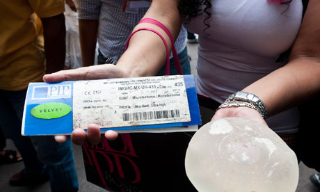 A woman holds her removed defective silicone gel breast implant