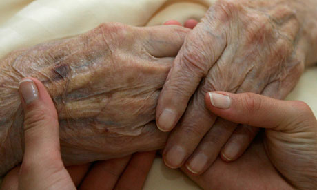 Carer holds the hand of an elderly woman