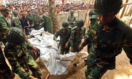 Soldiers help carry the bodies of workers killed in the fire at a garment factory in Dhaka.