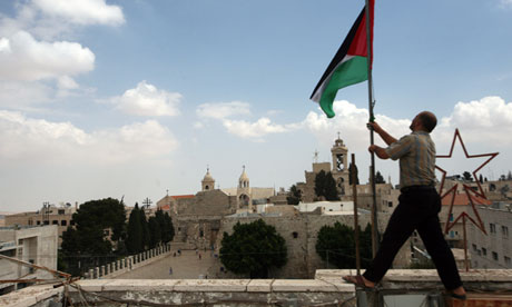 A Palestinian man fixes a national flag in Bethlehem