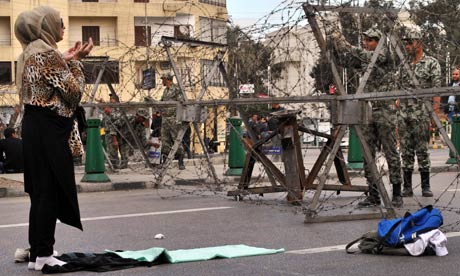 A Egyptian woman prays in front of security forces