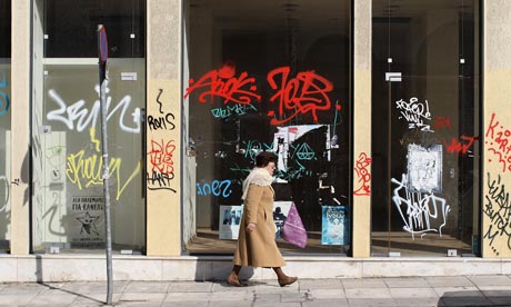 A woman walks past a closed-down shop in Athens