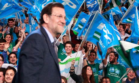 People's partys supporters wave flags as Mariano Rajoy arrives at a campaign rally in Seville