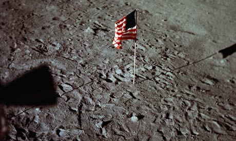 A US flag is surrounded by astronauts' footprints on the surface of the moon