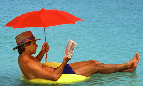 Man in swimming trunks reading while floating in sea