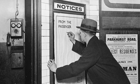 Man writing on complaints poster at London underground station