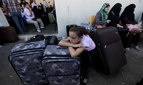 A girl rests on her luggage as she and her family wait to cross into Egypt at the Rafah crossing.