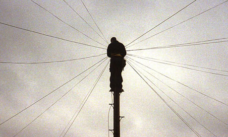 A telephone engineer at work up a pole