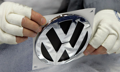 A factory worker holds a Volkswagen emblem
