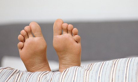 Close-up on the feet of a woman lying on a striped duvet