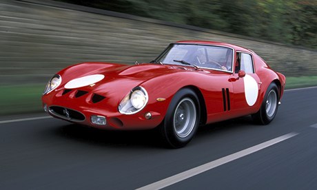 Red 1960s Ferrari driving along a road