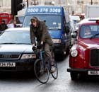 A cyclist rides his bike in London traffic.