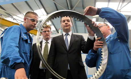 George Osborne looking at a round industrial part at a factury