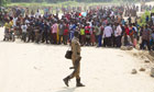 A Ugandan polie officer surveys a crowd of refugees from the Democratic Republic of Congo