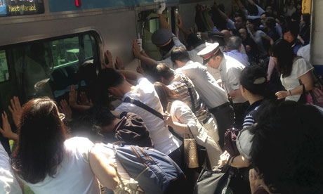 Train passengers and rail staff push a train car to rescue a trapped woman at Minami Urawa station.