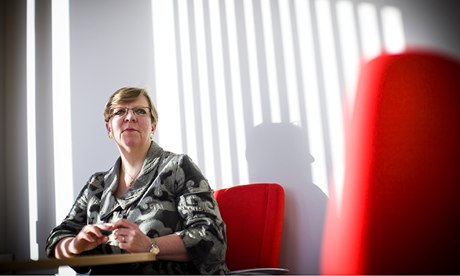 Alison Saunders pictured on a red chair with the reflection of venetian blind on wall behind her