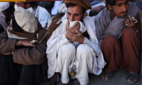 Refugees at the Gulan camp in Khost province, Afghanistan, crouching on ground