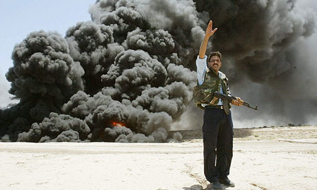 An Iraqi policeman shouts instructions at the scene following an attack on an oil pipeline