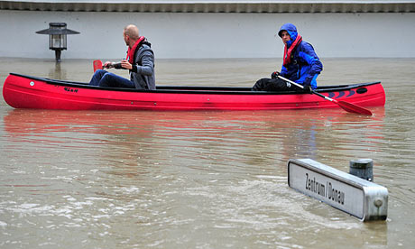 A canoe is steered past a street sign for the Danube river and the city centre of Passau, Germany, 